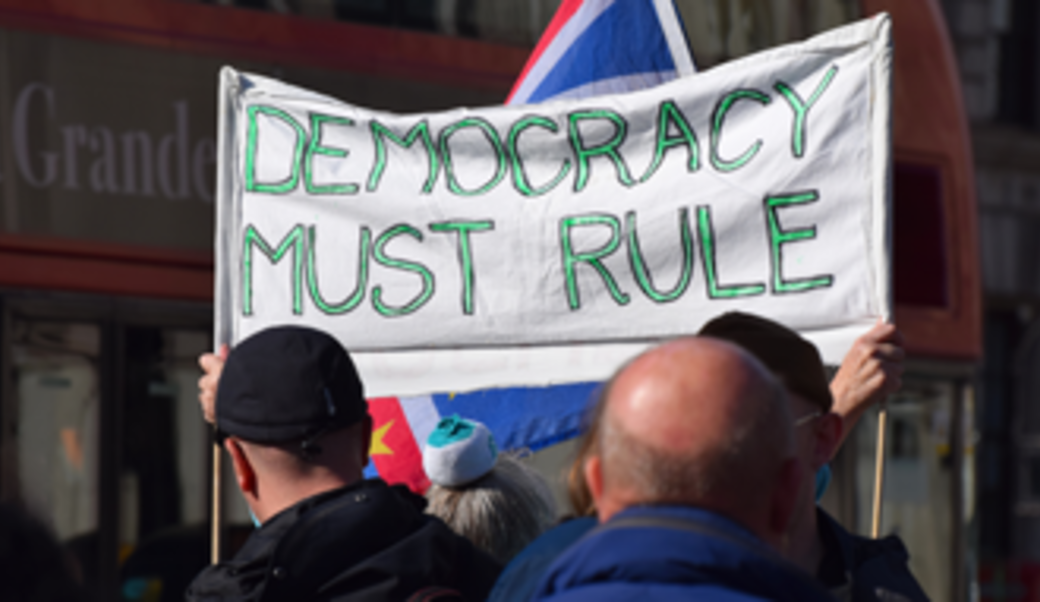 Protesters in London with a sign that says 'Democracy must rule'