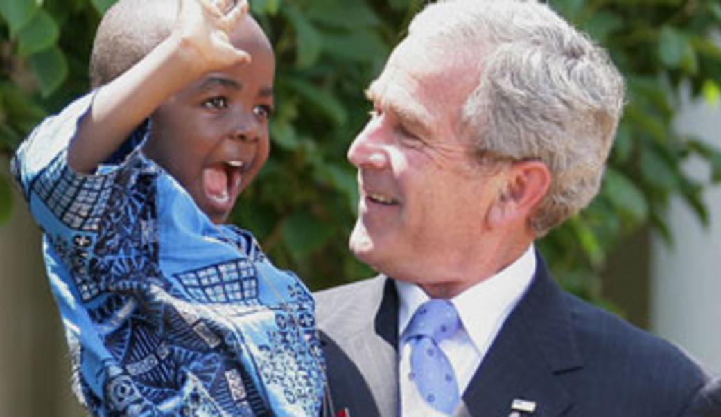 George Bush holds Kunene Tantoh, a young child, in his arms as both laugh
