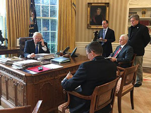 Donald Trump on the phone surrounded by advisors