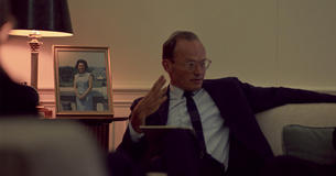McGeorge Bundy sitting on couch next to framed photo of Lady Bird Johnson