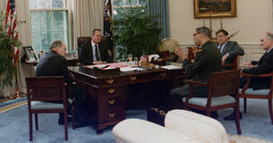 Secretary of State Colin Powell talking to President George H. W. Bush and others in the Oval Office
