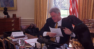 President Bill Clinton on the phone in the Oval Office alongside Buddy the dog