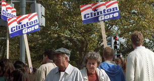 People holding up Clinton Gore campaign signs