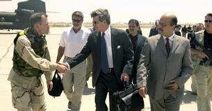 L. Paul Bremer III shakes hands with American military member while walking at the Baghdad International Airport.