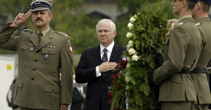 Robert Gates stands with his hand over his heart as he pays respect to fallen soldiers.