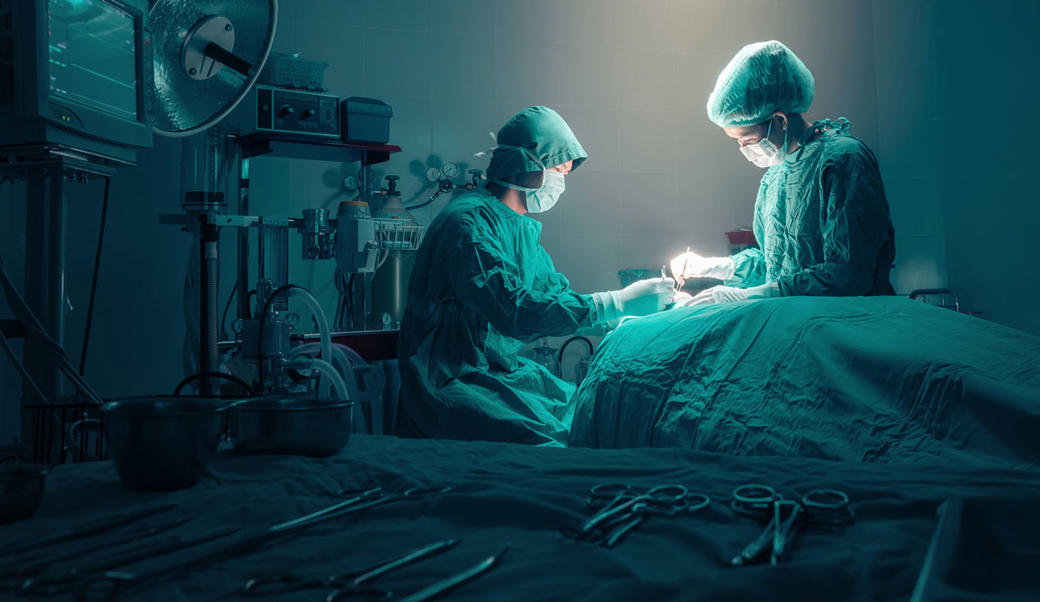 Doctors preforming surgery in a dimly lit operating room