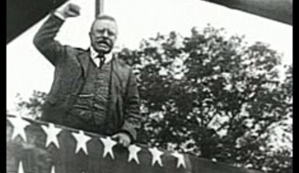 Theodore Roosevelt at a rally with fist raised