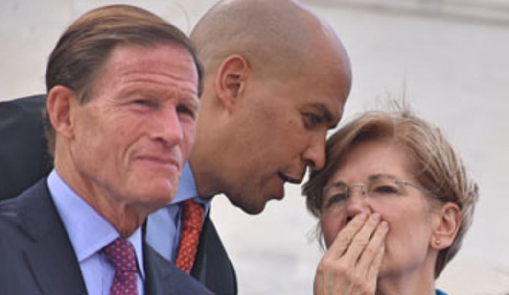 Corey Booker whispers to Elizabeth Warren; Senator Blumenthal in the foreground