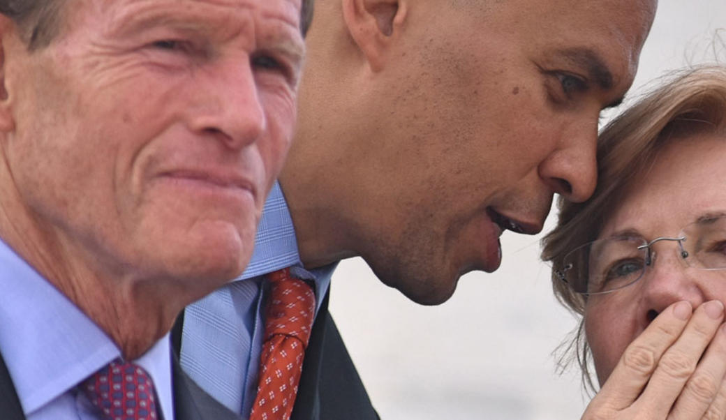 Corey Booker whispers to Elizabeth Warren; Senator Blumenthal in the foreground