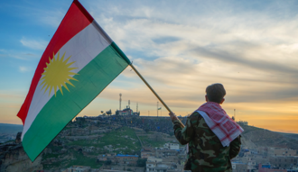 Man holding Kurdish flag at sunset