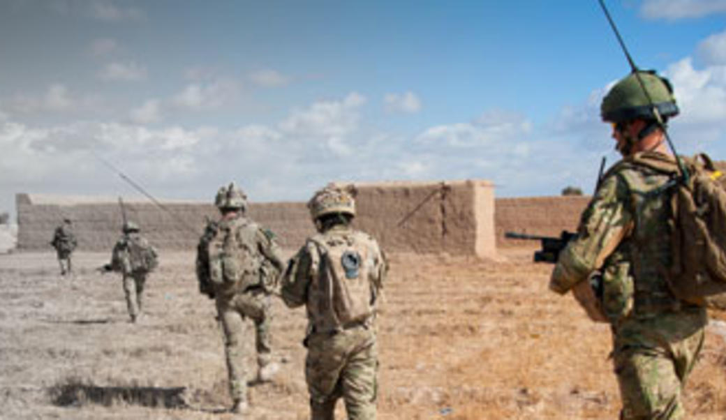 Soldiers walking across barren landscape