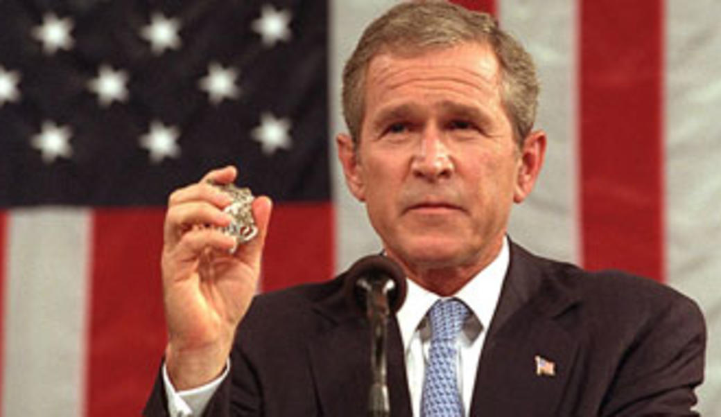 George W. Bush speaking in front of American flag