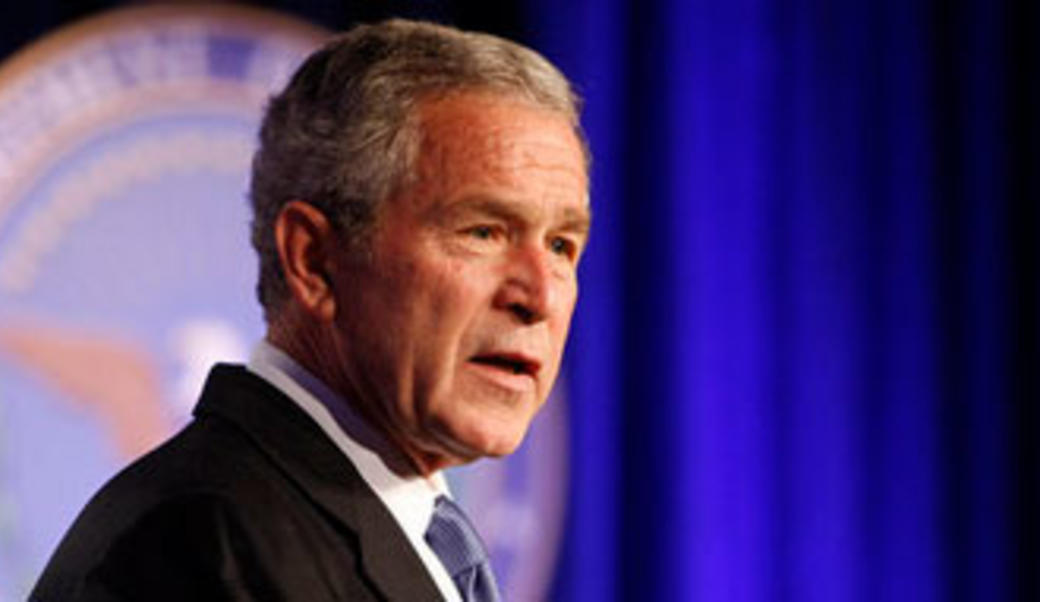 George W. Bush giving speech in front of dark blue flag