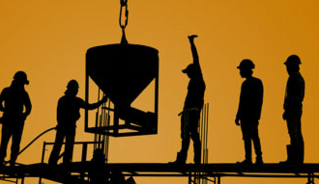 Workers pouring concrete against orange sky