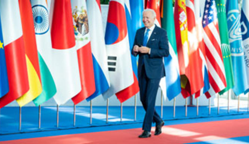 Biden walking in front of a line of international flags