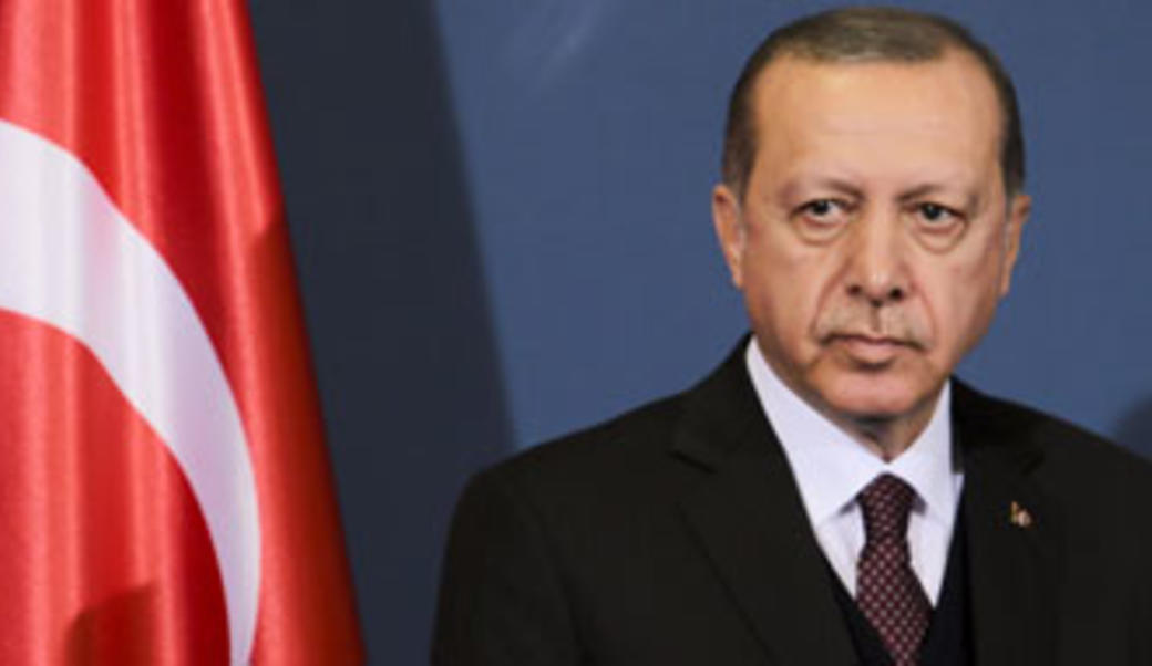 Erdogan standing in front of the Turkish flag