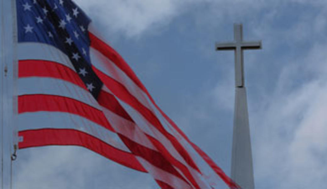A Christian cross in the background behind an American flag