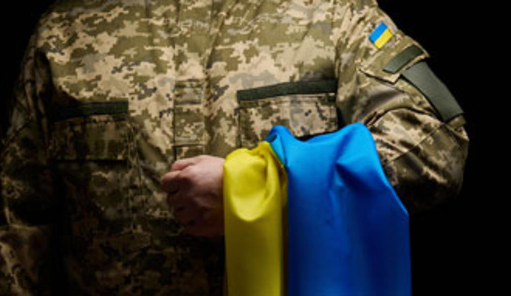 image of soldier holding Ukrainian flag