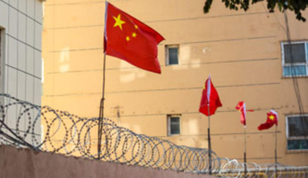 Chinese flags behind barbed wire in Xinjiang
