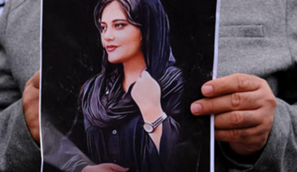 Man holding picture of Amini, who died in Iranian police custody