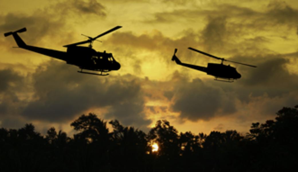 two helicopters flying over yellow-orange sky