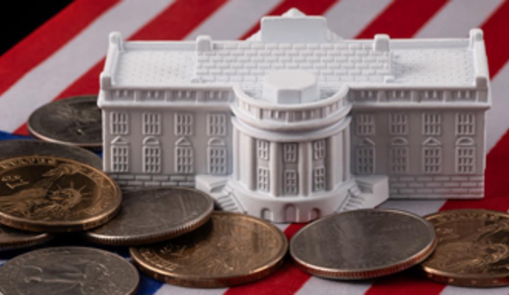 small replica of White House and coins on American flag