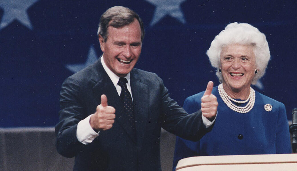 George H. W. Bush giving a thumbs up next to his wife, Barbara
