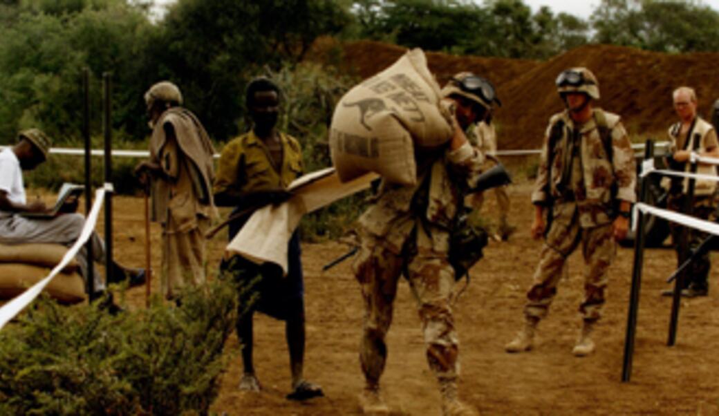 American soldier lifting bag of grain in Somalia during George H. W. Bush presidency