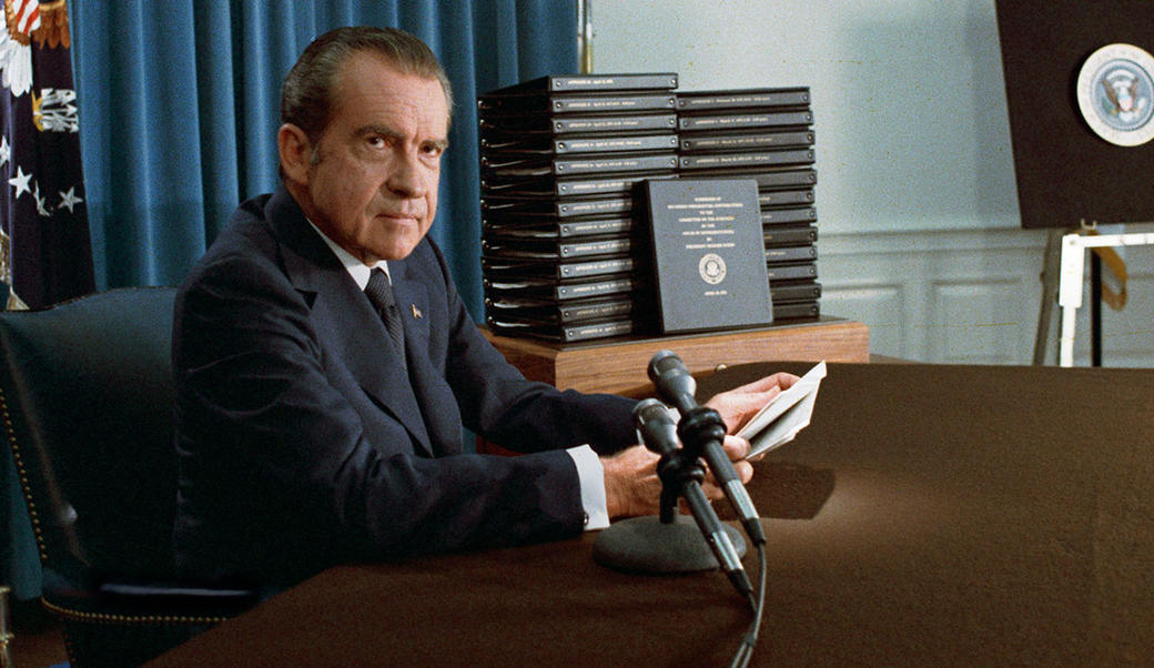 Nixon sitting in front of a stack of tape transcripts 