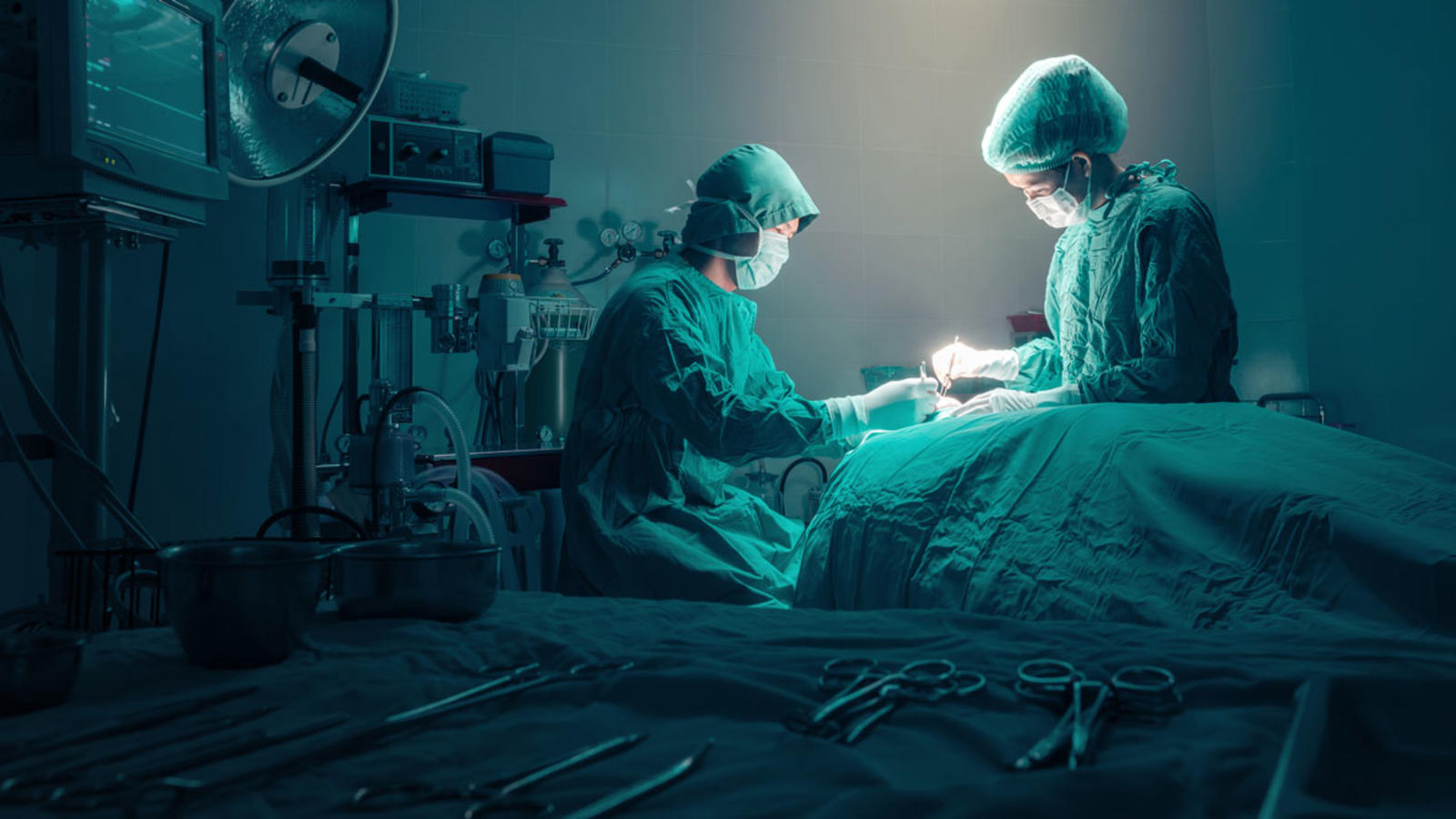 Doctors preforming surgery in a dimly lit operating room